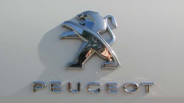 Un primer plano del león Peugeot y la palabra Peugeot en un coche blanco