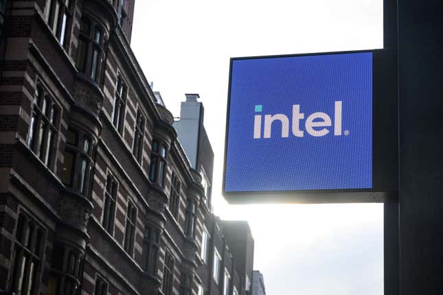 Intel logo on a black pole covering the sun, a brick building with windows can be seen in the back