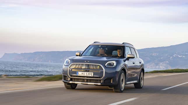 A photo of a blue Mini electric car driving on a highway. 