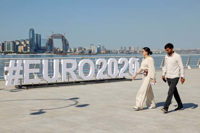 a couple walk past a sign for #euro2020