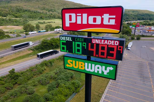 FILE - Trucks and cars drive by a Pilot Travel Center sign displaying fuel prices, June 20, 2022, in Bath, N.Y. The clock is ticking for Cleveland Browns owner Jimmy Haslam and his family to decide whether to sell their remaining stake in the Pilot truck stop chain to fellow billionaire Warren Buffet&#39;s Berkshire Hathaway company. A trial had been scheduled to start Monday, Jan. 8, 2023, in Delaware in a dispute over accounting practices at Pilot Travel Centers. (AP Photo/Ted Shaffrey, File)