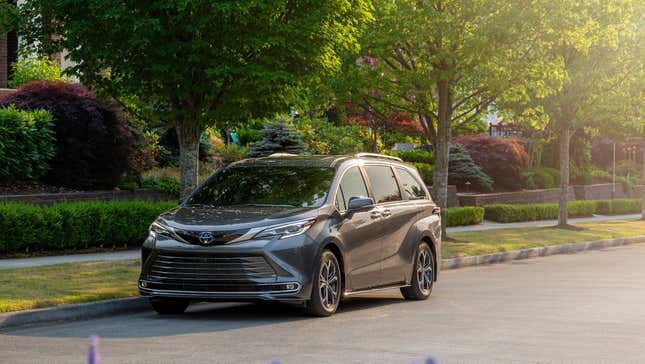 A gray sienna parked in front of trees