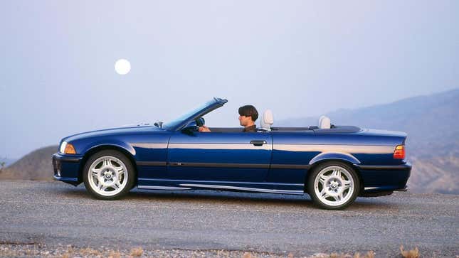 A side view of an E36 cabriolet with the roof down in front of the moon