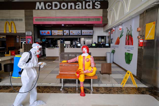 A worker sanitizes a bench and novelty Ronald McDonald figure outside a McDonald’s restaurant at the Ambience Mall in New Delhi, India. 