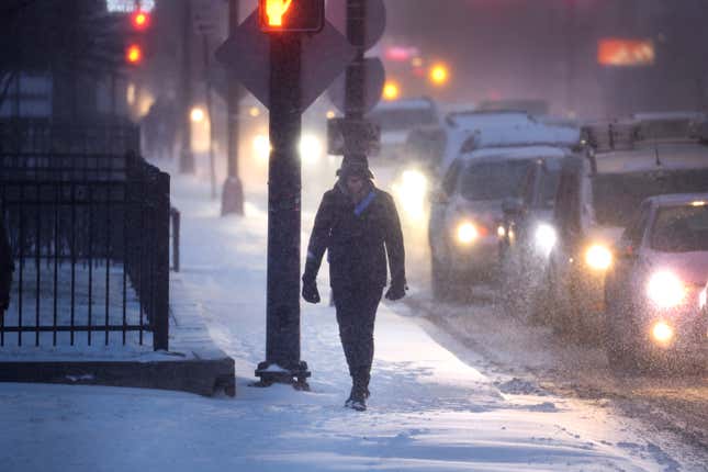 A pedestrian navigates a snow-covered sidewalk as temperatures hang in the single-digits on December 22, 2022 in Chicago, Illinois