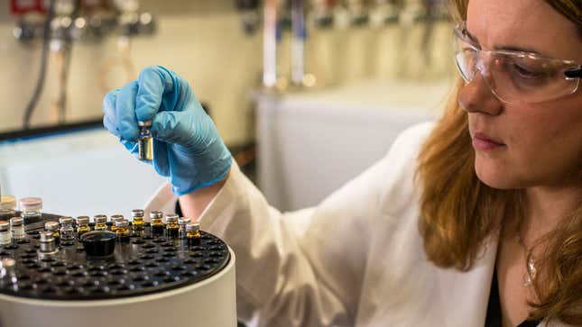 A photo of a scientist examining small vials of fuel. 