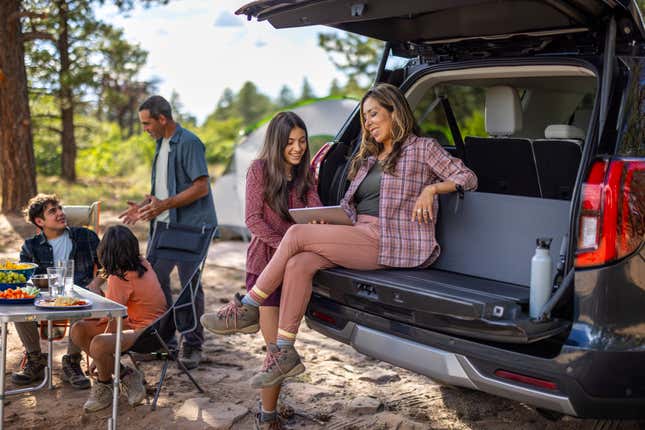 A photo of a family using the Expedition's split tailgate to sit near a campsite