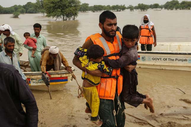 Rescue workers help evacuate people from their flood-hit homes following heavy monsoon rains in Rajanpur district of Punjab province on August 27, 2022.