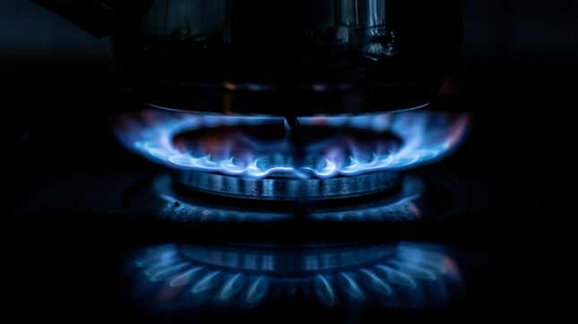 A flame on a gas stove with a pot sitting above it.