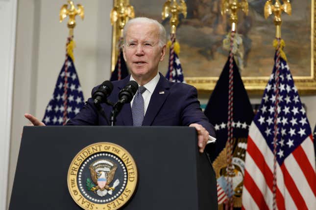 President Joe Biden delivers a speech at a podium in front of a line of US flags.