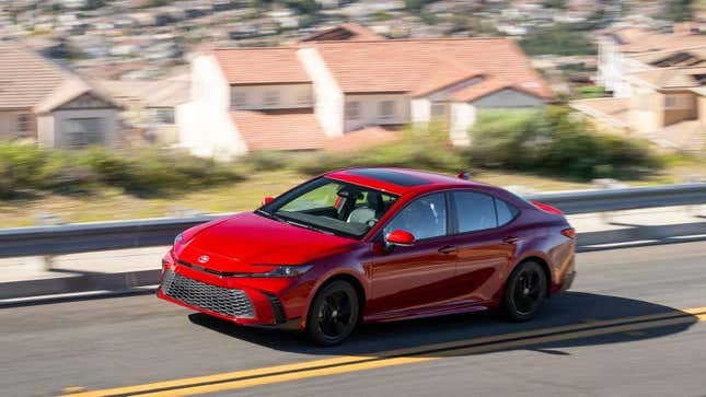 A red camry driving in the suburbs