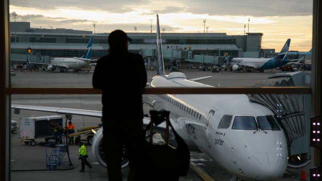 A photo of someone looking out at planes through an airport window. 