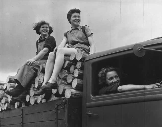 Landgirls of the Timber Corps sit on the neatly stacked fruits of their labour, as a truck takes them home after a hard day's work at a timber camp in Bury St Edmunds