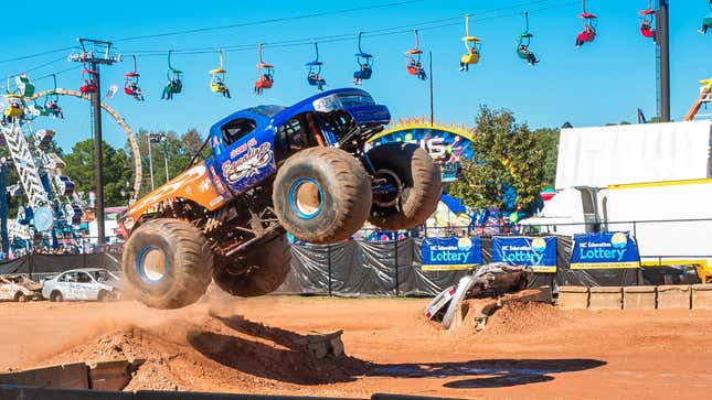 Une photo d’un monster truck bleu sautant dans les airs. 