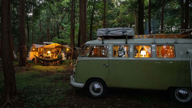 A green VW Splitscreen van parked in a forrest 