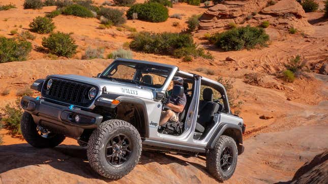 A Wrangler driving up a rock with the doors off