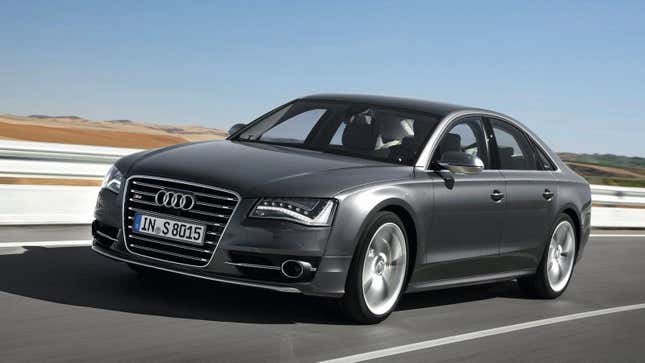 A gray 2013 S8 driving in front of a guard rail