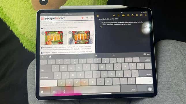 An iPad Pro showing a keyboard and two screens on a couch.