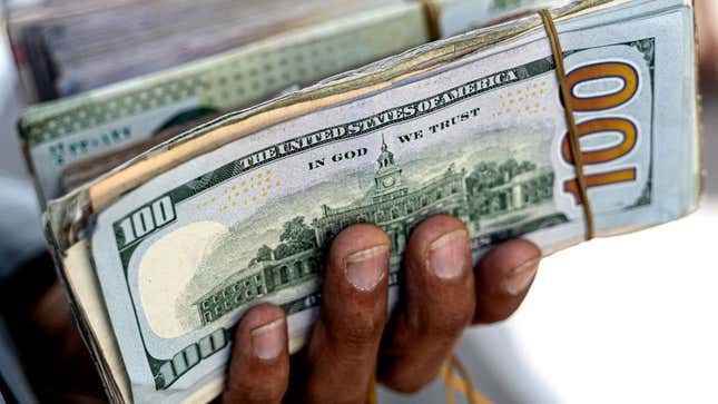 A man holds a stack of 100 dollar bills in his hand. 