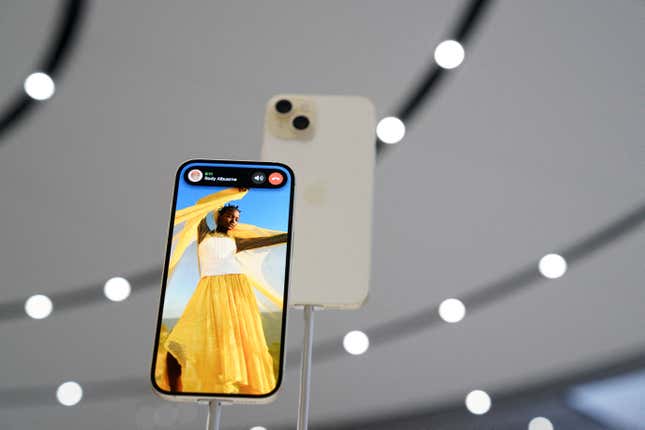 Two iPhones on display at an Apple event. One shows a woman on the phone background and an ongoing call.