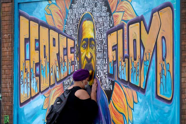 FILE - Damarra Atkins pays respect to George Floyd at a mural at George Floyd Square, Friday, April 23, 2021, in Minneapolis. In a new study, Black Americans expressed broad concerns about how they are depicted in the news media, with majorities saying they see racist or negative depictions and a lack of effort to cover broad segments of their community. (AP Photo/Julio Cortez, File)