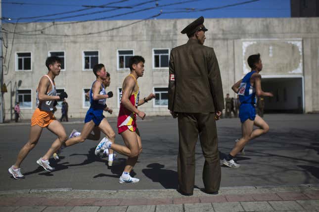 Marathon runners pass by a North Korean soldier.