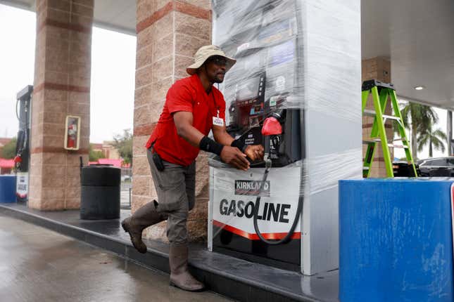 A gas station attendent in Naples, Florida, wraps a pump in plastic ahead of Hurricane Milton