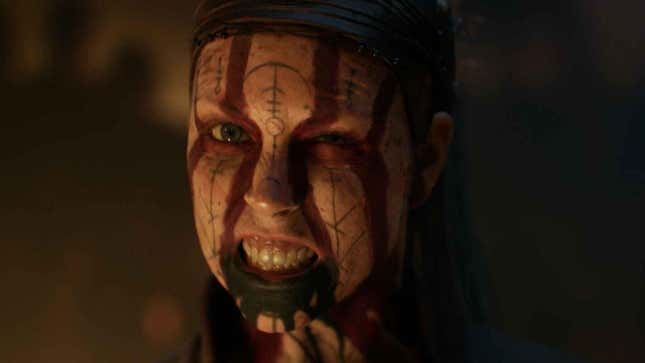 An angry woman with face paint in rune like lettering bears her teeth