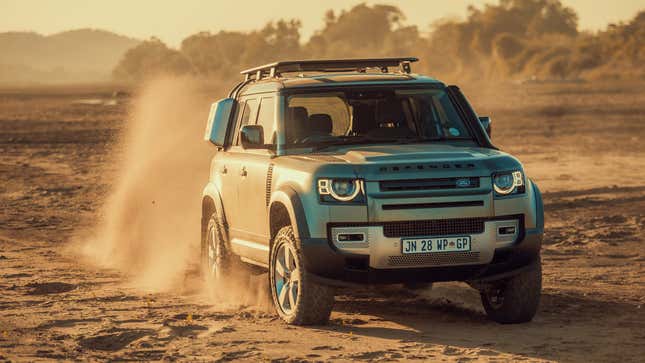 Silver Land Rover Defender front three-quarter angle view driving on dirt