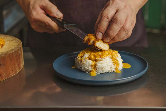 hands placing chicken patty on rice