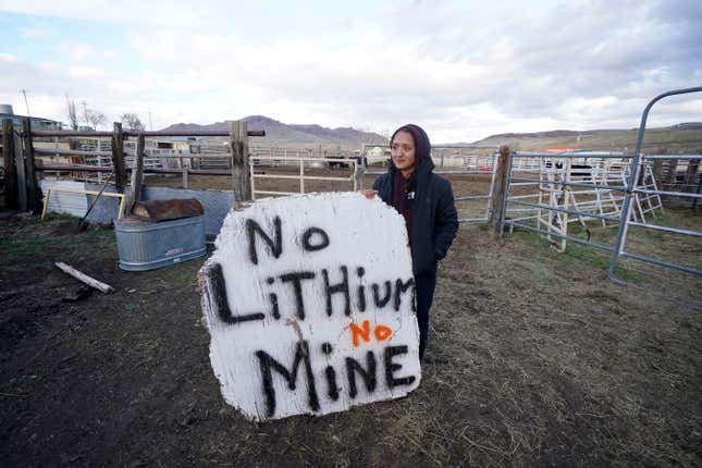 FILE - Daranda Hinkey, a Fort McDermitt Paiute and Shoshone tribe member, holds a large hand-painted sign that reads, &quot;No Lithium No Mine,&quot; at her home on the Fort McDermitt Indian Reservation, April 24, 2023, near McDermitt, Nev. A federal judge in Nevada has dealt another legal setback to tribes trying to halt construction of a huge lithium mine they say is near the sacred site of an 1865 massacre along the Oregon border. (AP Photo/Rick Bowmer, File)