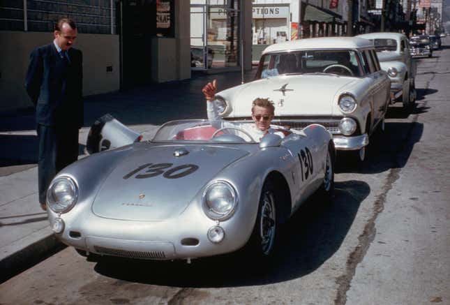 James Dean sitting in his silver Porsche giving a thumbs up while parked on the side of the road