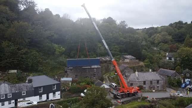 A screenshot showing a truck being lifted above houses in a small town. 