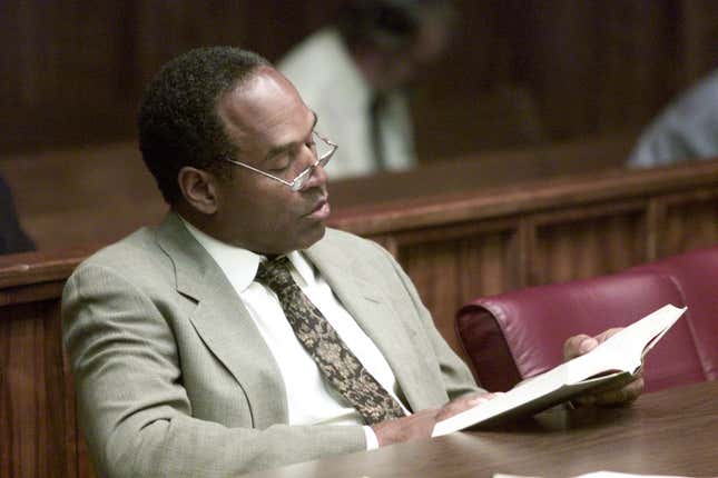 Former NFL star O.J. Simpson reads a book before the start of the third day of jury selection in a “road rage” trial October 11, 2001 in Miami, FL. 