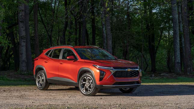 An orange Chevy Trax parked in front of some trees