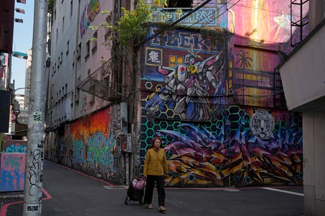 A resident walks past a graffiti in Taipei, Taiwan, Thursday, Jan. 11, 2024. Beijing&#39;s threats to use force to claim self-governed Taiwan aren&#39;t just about missiles and warships. Hard economic realities will be at play as voters head to the polls on Saturday, though the relationship is complicated. (AP Photo/Ng Han Guan)