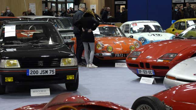 A photo of two people talking next to a car on display at an auto show. 