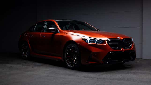 Front 3/4 view of a matte orange 2025 BMW M5