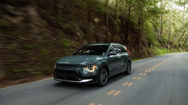 A blueish Kia Niro driving in the woods