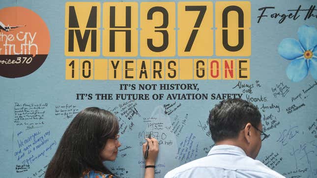 A photo of people signing a wall dedicated to MH370. 