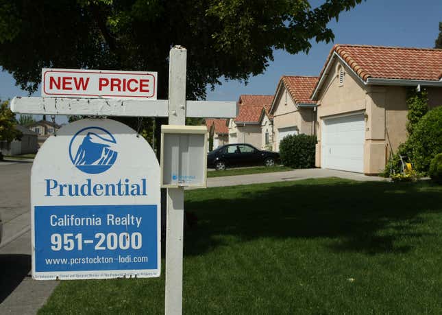 A for sale sign advertises a reduced price in front of homes for sale.