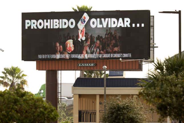 A billboard reads “Never Forget” (in Spanish) and shows U.S. President Donald Trump throwing a roll of paper towels when he visited Puerto Rico after Hurricane Maria in 2017. 