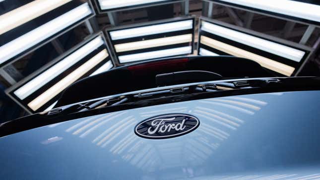 A photo of a Ford logo on the back of a blue electric car. 