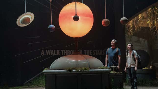 Joel and Ellie look at a diorama of the solar system.
