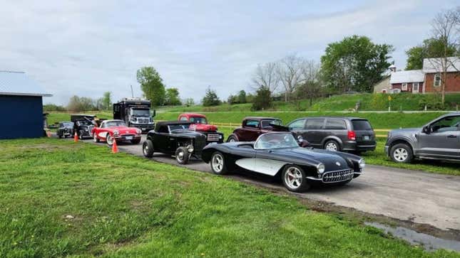 A photo of classic cars lined up on a dirt road. 