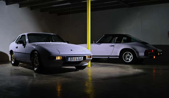 Two Porsches in a pale purple color known as "moonstone" sit parked in a dark shadowy room with a bright yellow pole between them.