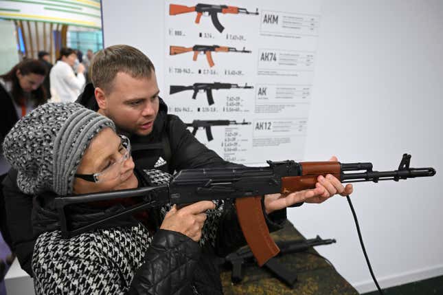 A woman holds a weapon as she visits a pavilion of the International exhibition &quot;Russia&quot; at VDNKh (The Exhibition of Achievements of National Economy) in Moscow, Russia, Saturday, Nov. 4, 2023. The vast show was put together under a decree from President Vladimir Putin and is seen as encouraging patriotism in the runup to the presidential election in March. (Maxim Blinov, Sputnik Host Photo Agency pool via AP)