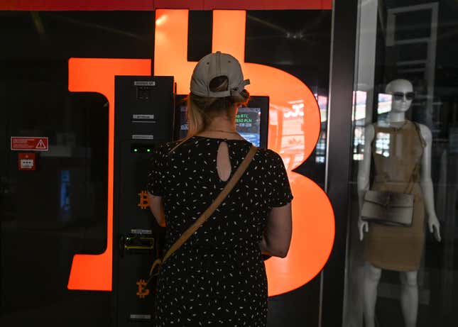 Une femme portant une robe et une casquette de baseball achète des bitcoins dans un kiosque