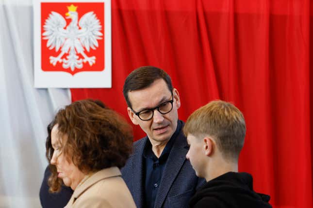 Poland&#39;s conservative ruling Law and Justice Prime Minister Mateusz Mazowiecki waits for his wife Iwona Morawiecka to cast her ballot during parliamentary elections in Warsaw, Poland, Sunday, Oct. 15, 2023. The outcome of Sunday&#39;s election will determine whether the right-wing Law and Justice party will win an unprecedented third straight term or whether a combined opposition can win enough support to oust it. (AP Photo/Michal Dyjuk)