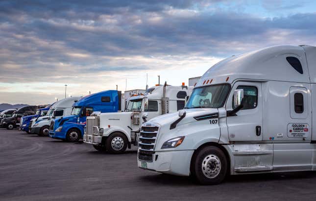 A line up of heavy duty trucks under a cloudy sky.